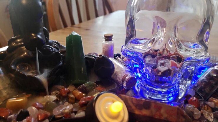 Samling af farverige healende krystaller og et mystisk spirituelt kranie på et træ køkkenbord med brændende røgelse.