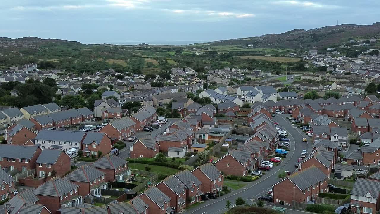 Nordwales' moderne boligkvarter med røde mursten under Holyhead-bjerget, luftfoto der bevæger sig mod højre.