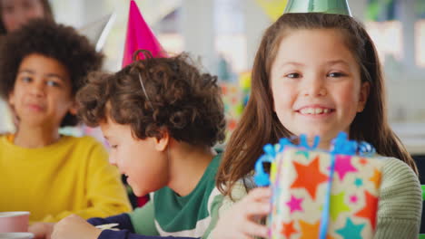 girl giving gift at birthday party with friends and parents at home