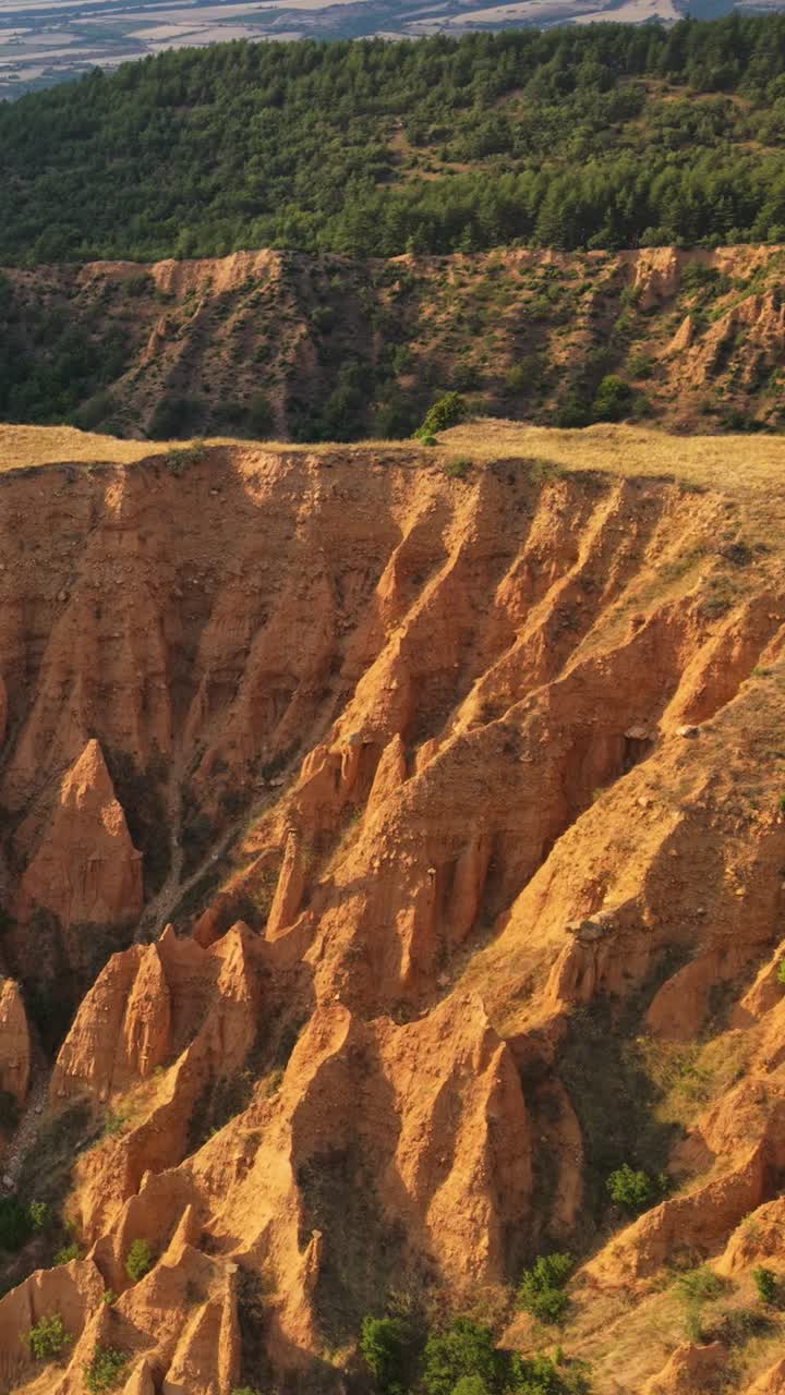 Aerial cinematic view of sandstone peaks at the Stob Pyramids Bulgaria framed by rural green valleys and mountain ridges