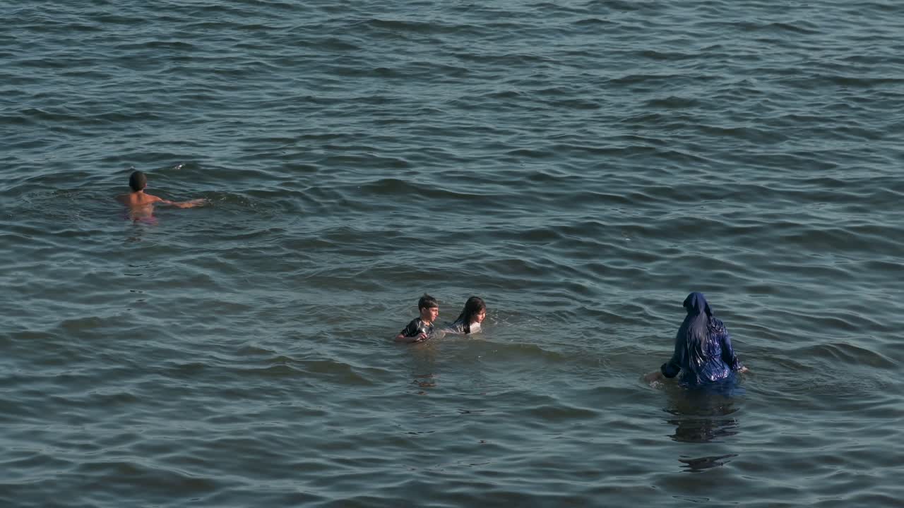 At Campello Beach on Costa Blanca, a family of swimmers delights in the calm Mediterranean waters in Alicante, Spain.