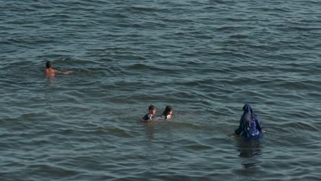 at campello beach on costa blanca, a family of swimmers delights in the calm mediterranean waters in alicante, spain.