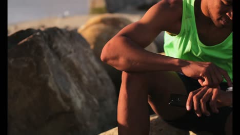 Hombre-Afroamericano-Usando-Smartwatch-En-La-Playa-Bajo-El-Sol-4k