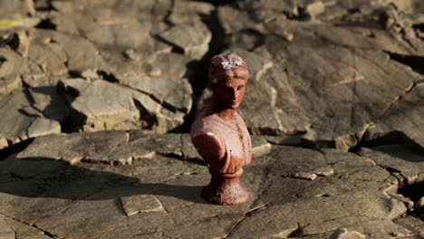 ancient statue of woman on rocky stones