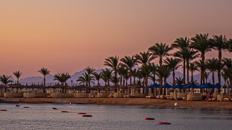 Time-lapse dell'alba sulla spiaggia di Hurghada con palme nel resort e maestosa silhouette montuosa alle prime luci dell'alba, Egitto, Africa