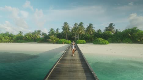 Mujer-Elegante-En-Traje-De-Baño-Blanco-Caminando-Por-Un-Muelle-De-Madera-En-Una-Isla-Tropical