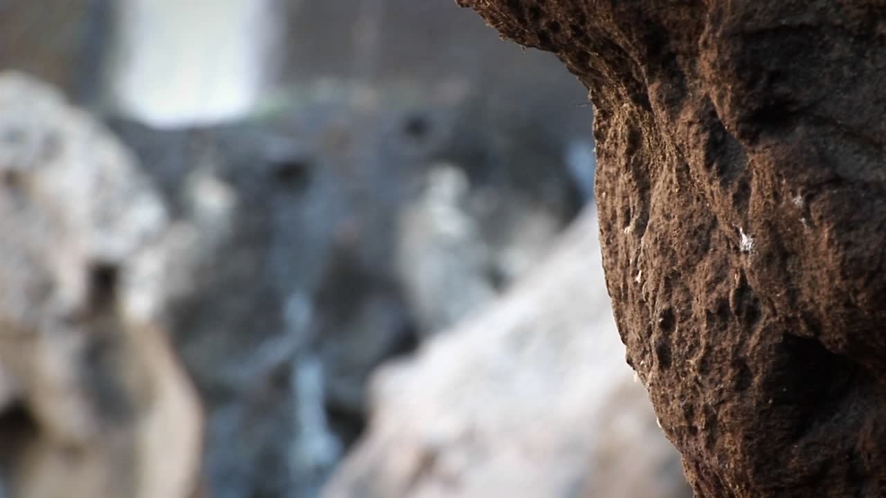 un escalador da un paso con una cascada al fondo