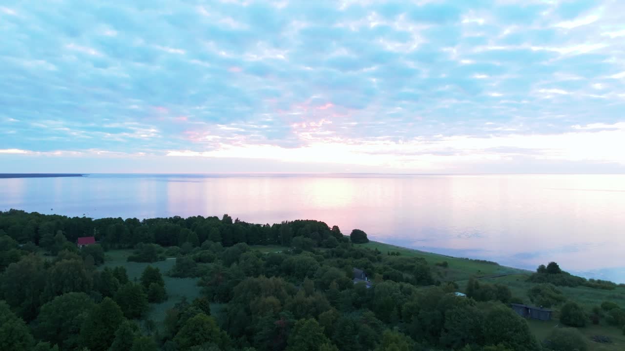 Calm sunset sea and a green inhabited coastline with houses