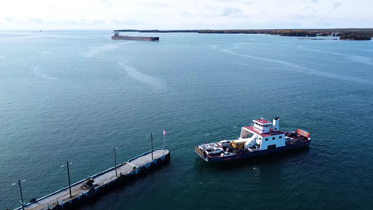 barco de ferry que sale del muelle con un buque de carga detrás
