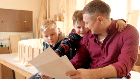 family, carpentry, woodwork and people concept. father teaches son carpentry.