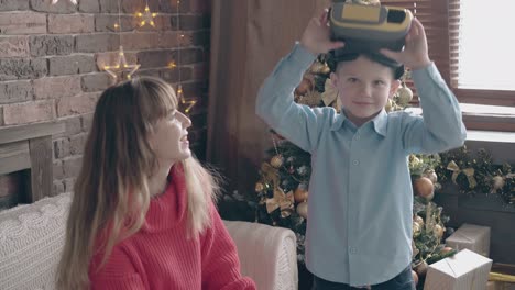 el pequeño hijo con gafas vr se divierte con su madre en el sofá