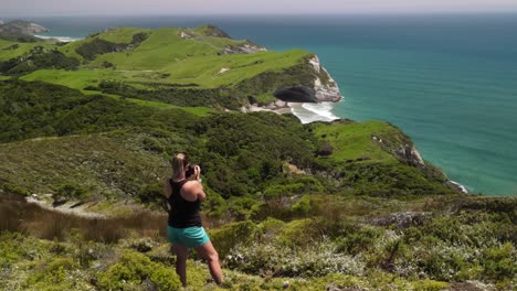 Young-blonde-traveler-with-camera-on-clifftop