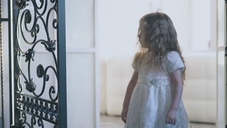 girl in white opens forged lattices and dances in doorway