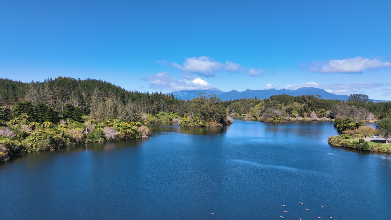 Drone flight of iconic Lake Mangamahoe view to snow covered Mt Taranaki New Zealand