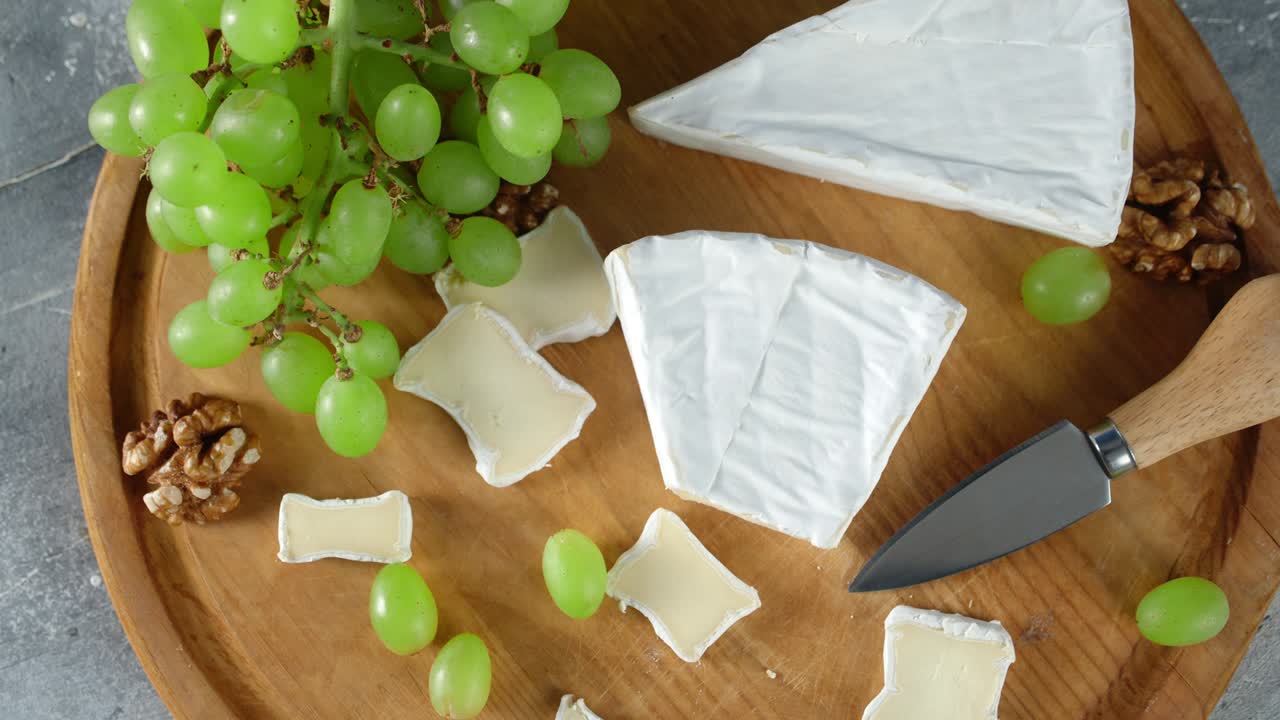 Slices of Camembert cheese on cutting Board slowly rotate.