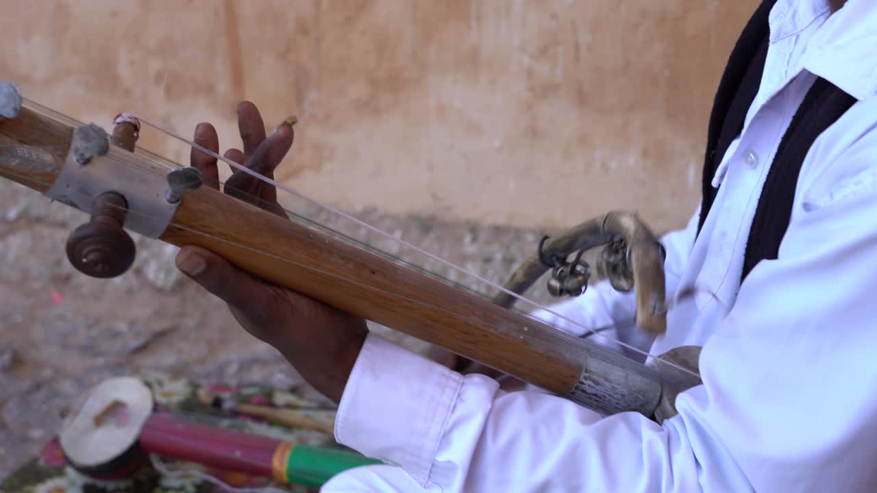 Musicista indiano che suona uno strumento musicale tradizionale per i turisti. India.