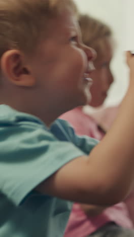 los niños controlan las consolas de juegos para jugar a videojuegos fascinantes en un fondo borroso. los niños pequeños y preescolares se sienten felices de ganar en casa de cerca