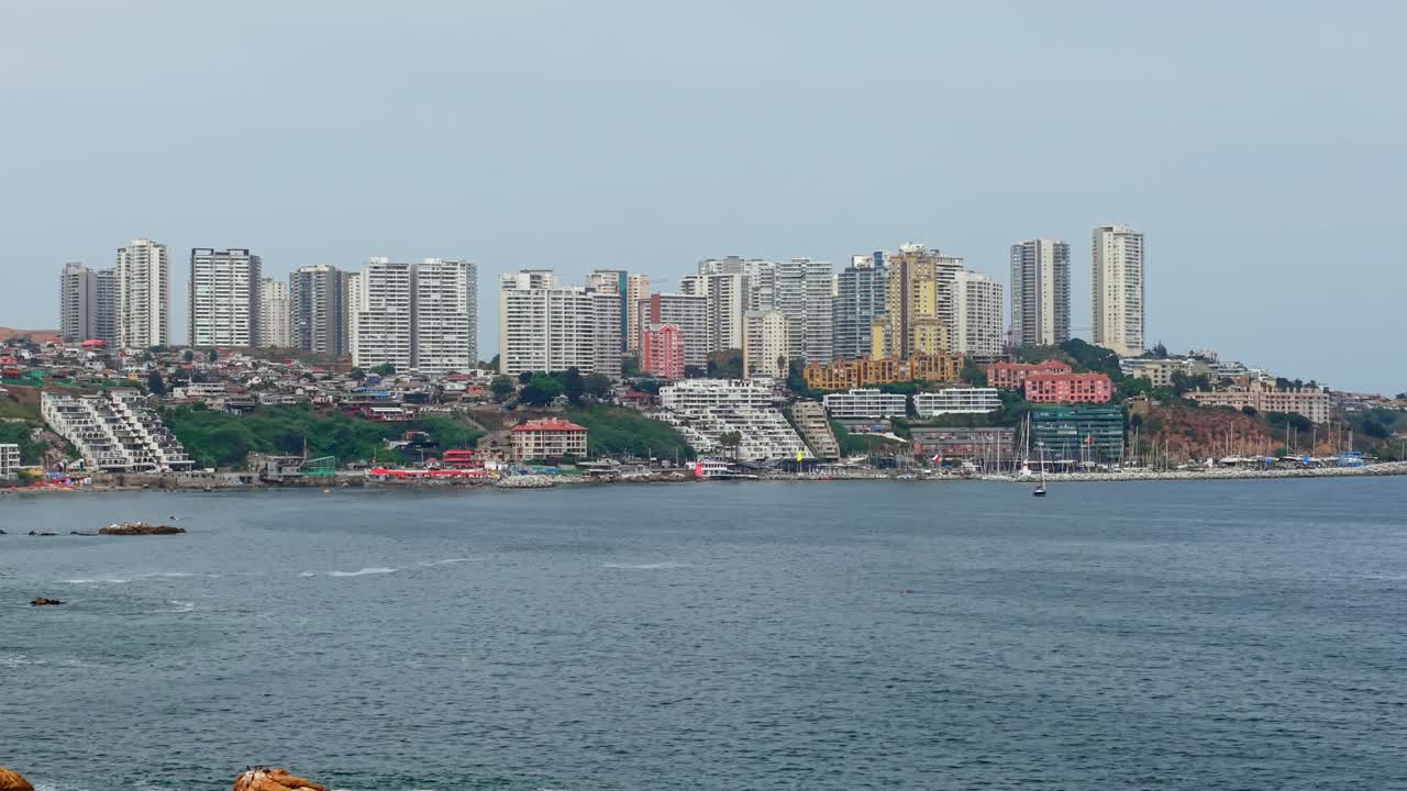 Veduta aerea della curva costiera e della barriera frangiflutti vicino a Playa Negra con gli edifici esclusivi della città di Concón, Cile, in una giornata nuvolosa