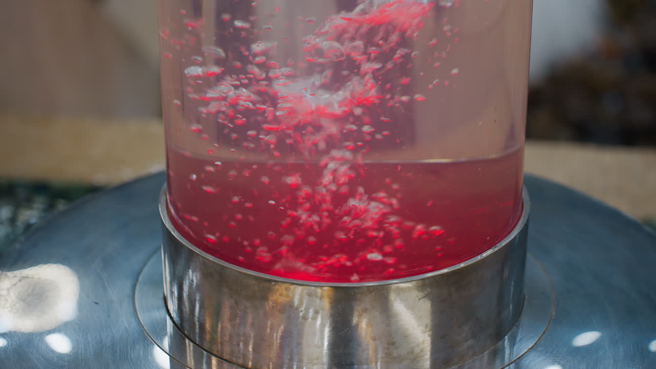Close-up of large cylindrical water feature with vibrant blue water and bubbles, showcasing an aesthetic and calming atmosphere in a mall or shopping center with glowing lights