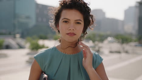 portrait of beautiful stylish hispanic woman looking pensive at camera running hand through hair in sunny urban city background