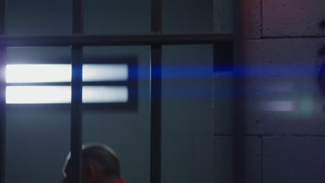 Close-Up-of-Prisoner-in-Orange-Uniform-Holding-Metal-Bars-in-Prison-Cell----------(Stock-Footage)