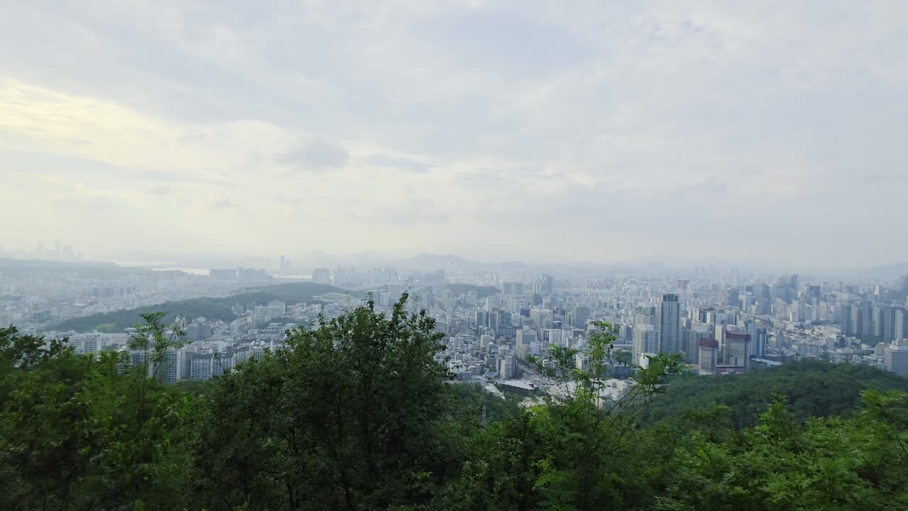 Seoul’s skyline at sunset, revealing the city’s high-rise buildings, Han River, and surrounding mountains under a warm, glowing sky - A panoramic panning shot captures