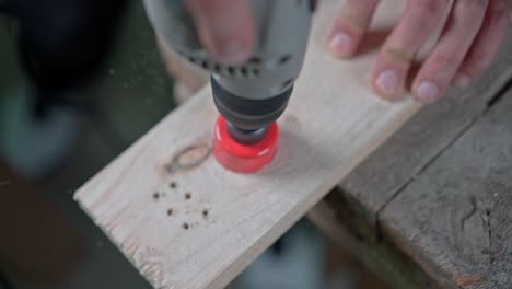 A drill with a circular nozzle cuts a circle in a wooden block