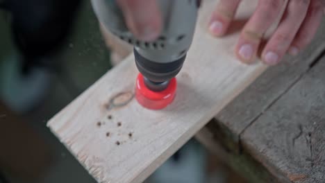 a drill with a circular nozzle cuts a circle in a wooden block