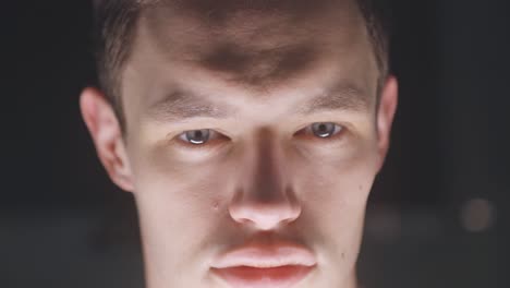 close-up shot of a young caucasian guy in front of a bright screen monitor