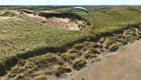 extreme paragliding, coastal flying, long shadows, sunny, beach and ocean waves, aerial, follow shot, langevelderslag beach, netherlands