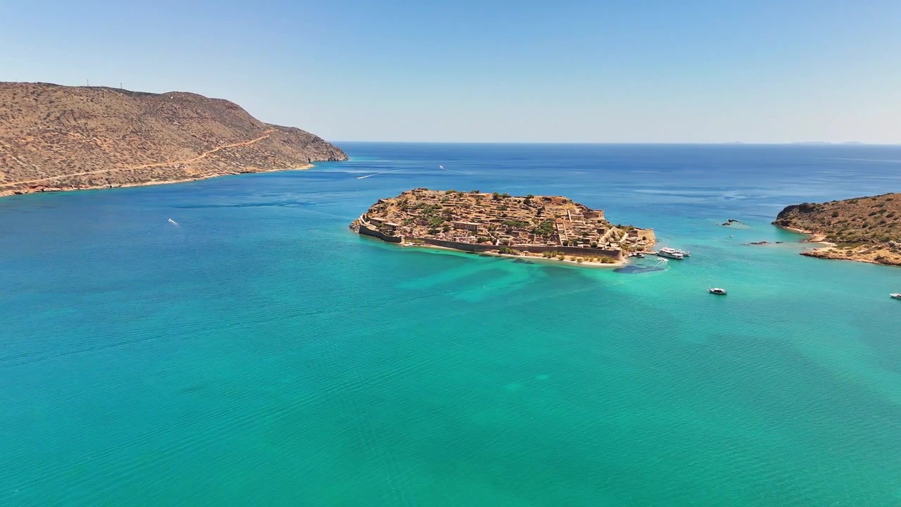 Spinalonga, resmi adıyla Kalydon, Elounda Körfezi'nde, Venedik surları ve tarihi kalıntılarıyla turkuaz sularla çevrili müstahkem kayalık bir ada olarak yükseliyor, Girit, Yunanistan.
