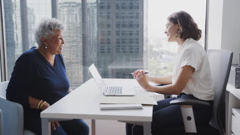 senior woman meeting with female financial advisor in office and signing contract