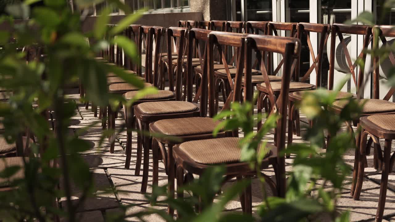wooden chairs in rows on a stone terrace framed by greenery ready for outdoor event