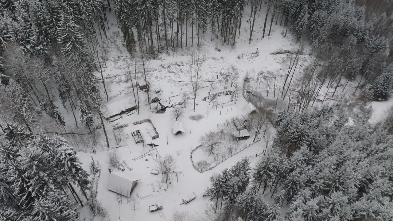 Prehistoric village of wooden houses and fences. Simple life in the middle of the forests. Snowy landscape in winter. Drone view
