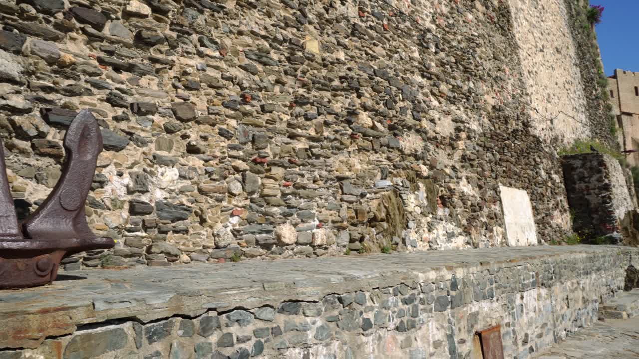 Enorme ancora arrugginita appoggiata contro il muro della fortezza a Collioure, nel Sud della Francia