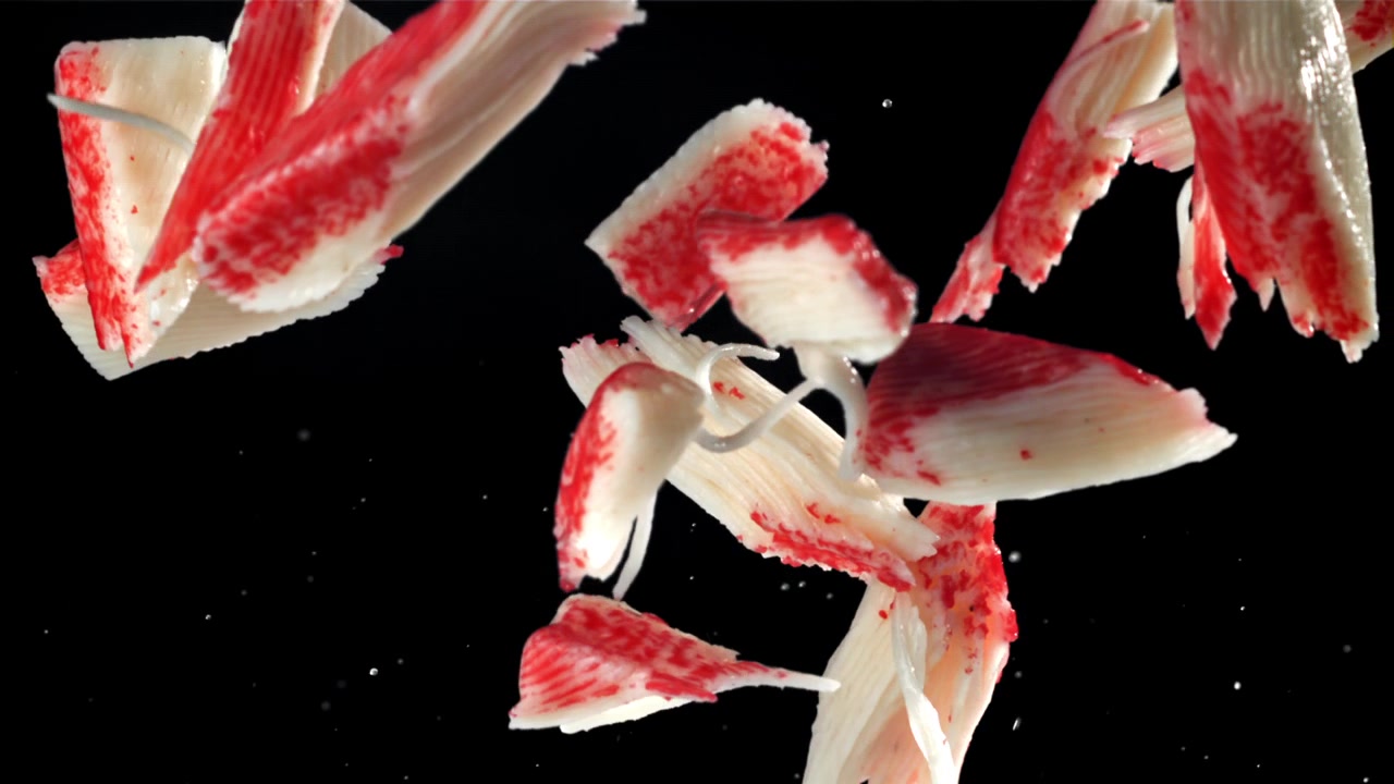 Imitation Crab Sticks Falling in Slow Motion on Black Background