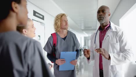 diverse doctors discussing work in corridor at hospital, slow motion