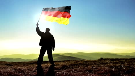 successful silhouette man winner waving german flag on top of the mountain peak. cinemagraph loop background