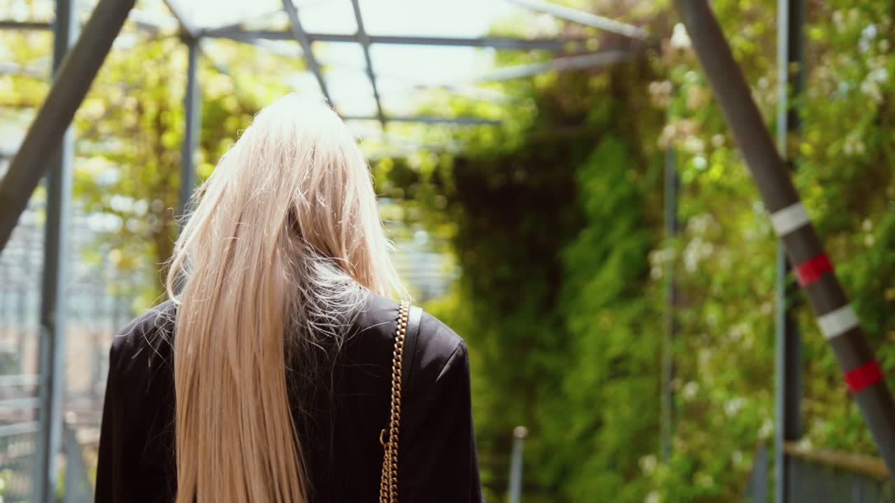A young woman walks through a park, looking back and laughing. Gimbal camera movement