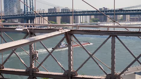 slow motion landscape of barge cargo shipping freight boat with manhattan brooklyn bridges structure east river new york city skyline cbd usa america travel transport tourism industry