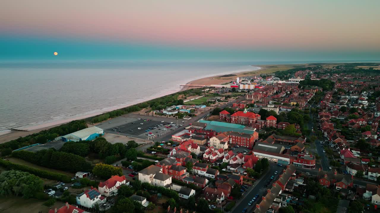 Sunset aerial footage of the seaside town and sand dunes in Skegness showing the pier, fairground rides in the East Lindsey district of Lincolnshire, England