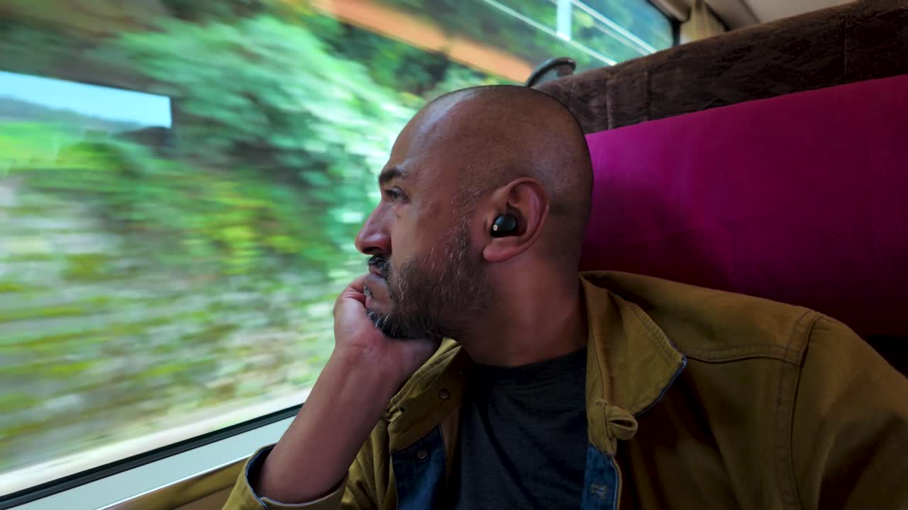 A serene moment of a man observing picturesque scenery during a train ride.