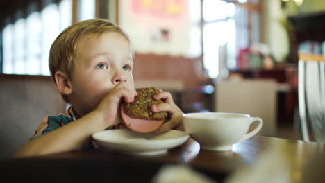 little boy eating sandwich in a cafe