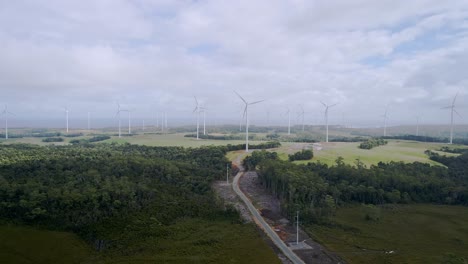 Amplia-Antena-De-Turbinas-De-Parques-Eólicos-Con-Bosque-En-Primer-Plano-En-La-Costa-Oeste-De-Tasmania,-Australia