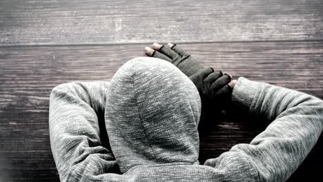 person in hoodie lying on wooden floor