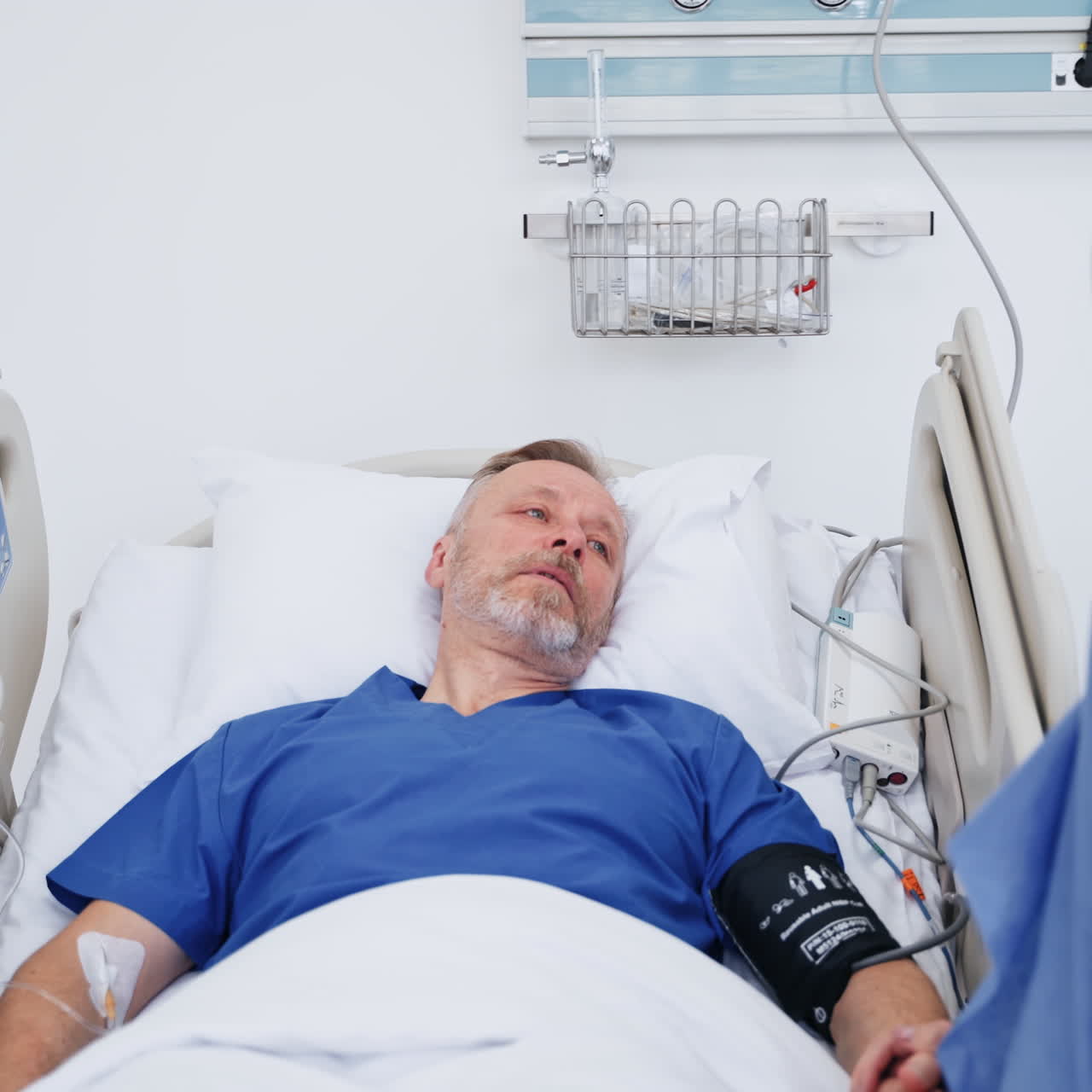 Woman visiting sick father. Senior man lying in medical bed and talking to a female visitor in hospital. Young woman supports the patient in clinic.