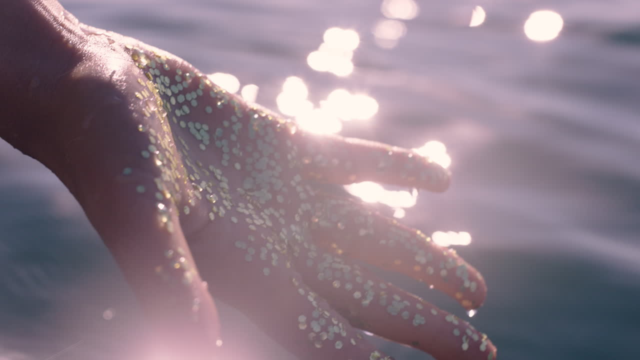 가까운 여성의 손이 물의 물결을 만지고 관광객이 보트 타기를 즐기고 있습니다.