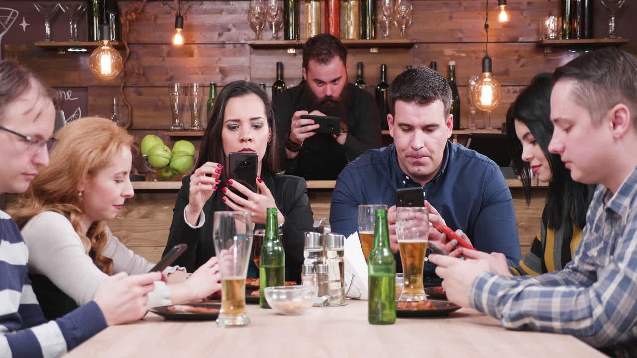 Group of friends using smartphones in a restaurant