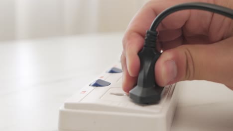 Close-up-Male-hand-plugging-in-a-power-cord-on-the-table