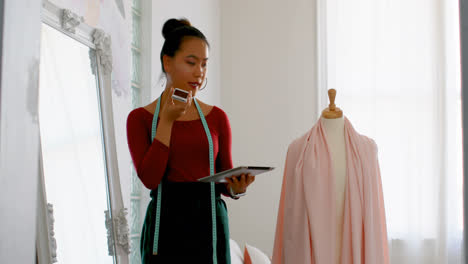 fashion designer talking on the phone while working on dress makers model 4k